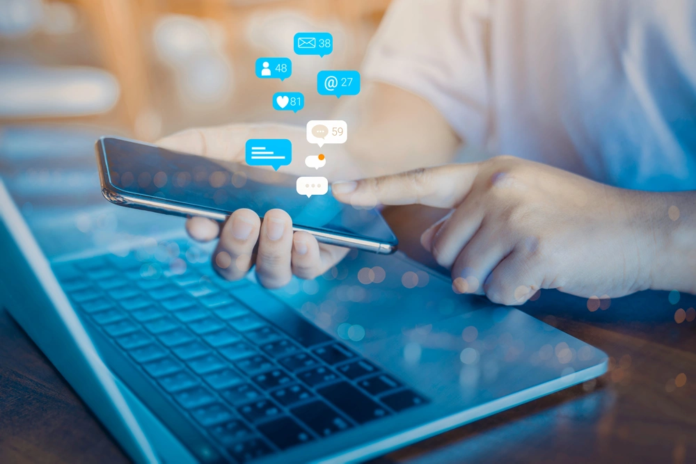 Person using a social media marketing concept on mobile phone with notification icons of like, message, comment and star above mobile phone screen.